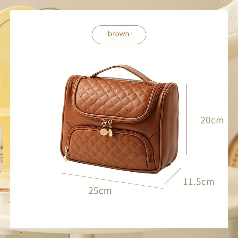 Brown quilted vanity bag with handle, front zip pocket, and coin charm pull.