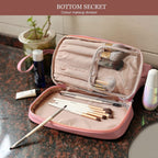 Pink cosmetic case with clear top window, open compartments, makeup brushes inside