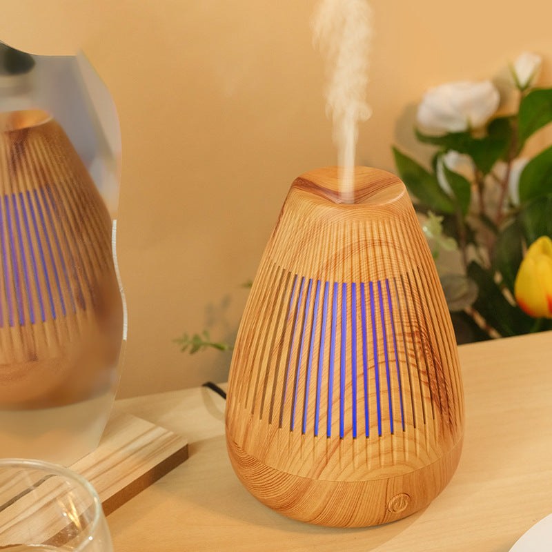 Ultrasonic essential oil diffuser, light wood grain, emitting a soft mist with blue LED lines