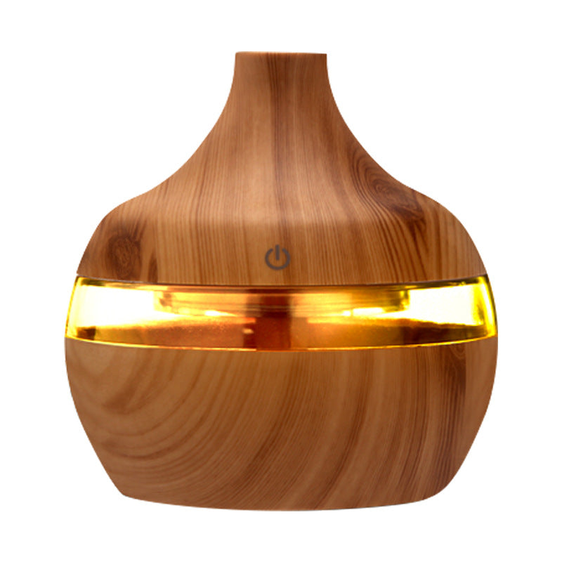 Wood grain aroma diffuser with amber/gold LED light band and power button on wood finish.