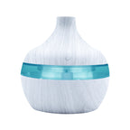 White wood-grain aroma diffuser with teal LED light band and power button.