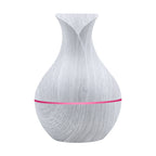 White wood-grain aroma diffuser with pink-magenta LED light band and power button.
