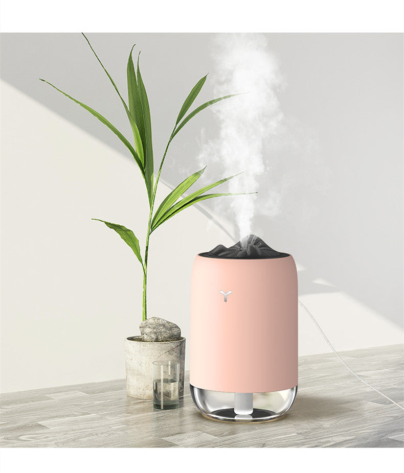 Pink USB aroma diffuser releasing mist, with black textured top and glass base