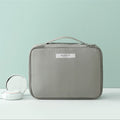 Gray compact makeup travel pouch with front handle and zip closure