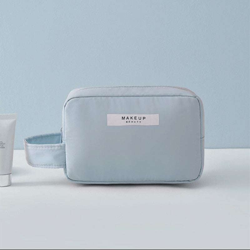 Light blue compact makeup travel pouch with front label and zip closure
