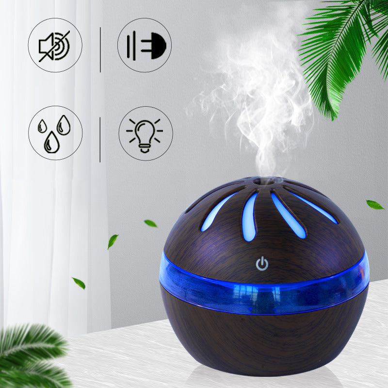 Dark wood-grain mist diffuser with blue base ring, glowing vents, visible vapor