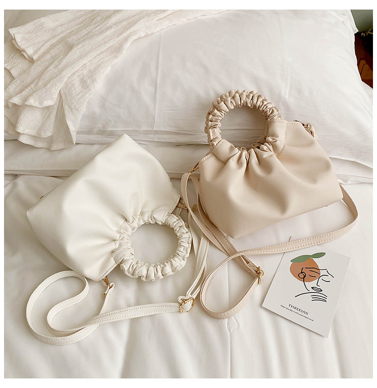 Cream ruched-top crossbody travel bag with drawstring rim and long crossbody strap