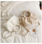 Cream ruched-top crossbody travel bag with drawstring rim and long crossbody strap
