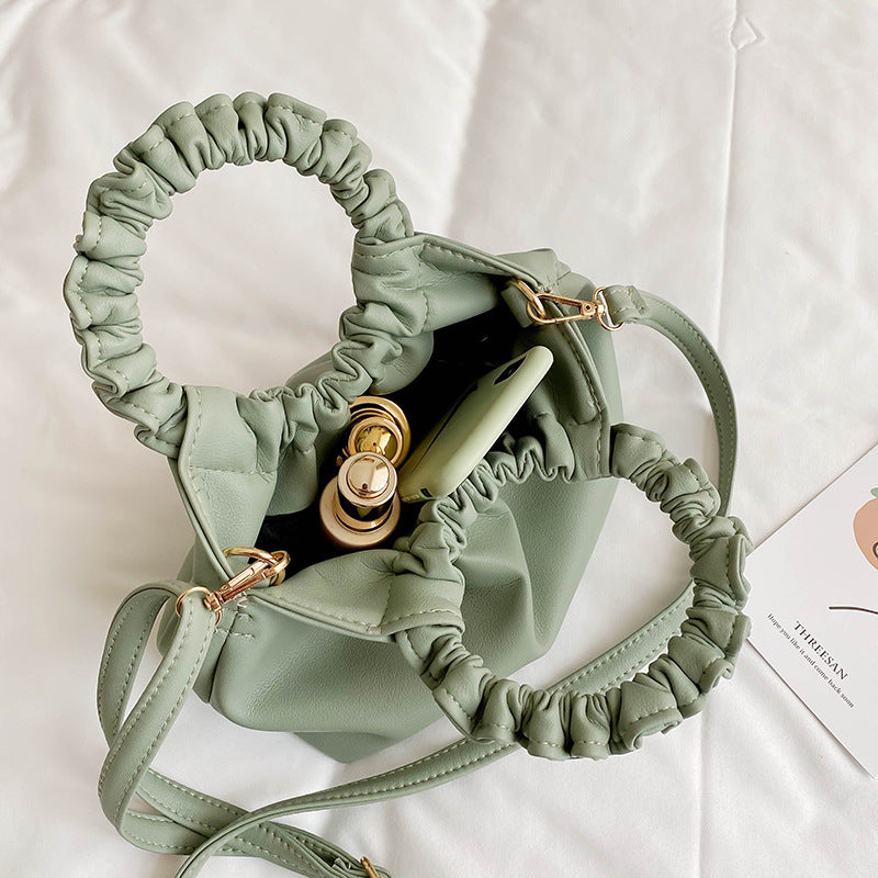Green crossbody travel bag interior view with ruched opening and clasp hardware