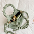 Green crossbody travel bag interior view with ruched opening and clasp hardware