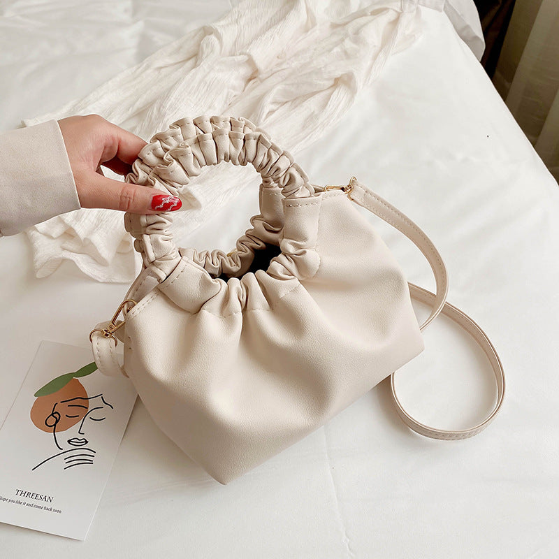 Cream ruched-top crossbody travel bag with loop handle, drawstring rim, and strap