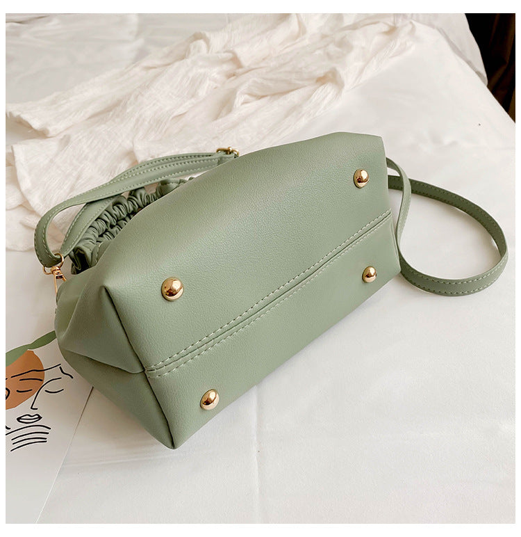 Green crossbody travel bag with snap buttons, ruched top, and adjustable strap