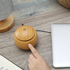 Wood grain aroma diffuser, light rounded base with removable top and fingertip pointing