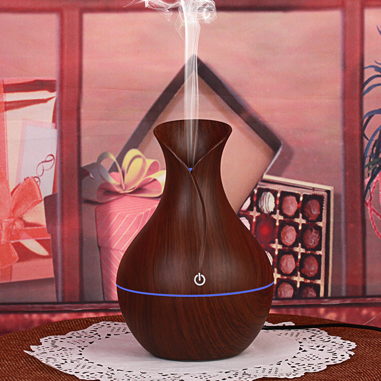 Wood grain aroma diffuser, dark teardrop shape with glowing power light and mist stream