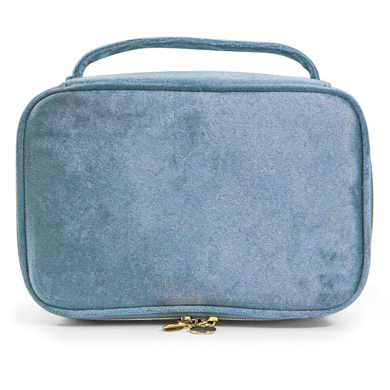 Soft travel cosmetic case in light blue with top handle and gold zipper pull