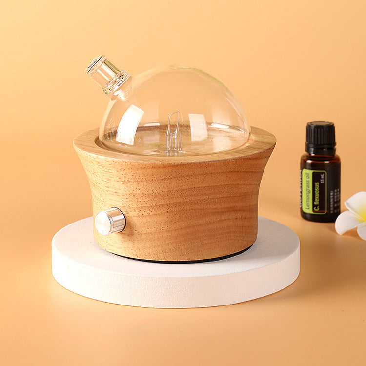 Wood aroma diffuser with clear glass dome, light wood base, and metal control knob