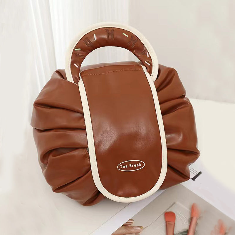 Brown drawstring wash bag with white trim, oval loop handle, and Tea Break patch