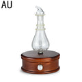 Aroma diffuser with glass atomizer bottle on dark wooden base and silver power button