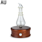 Aroma diffuser with glass atomizer bottle on dark wooden base and silver power button