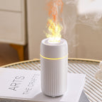White aroma diffuser with vapor plume from top nozzle, on table.