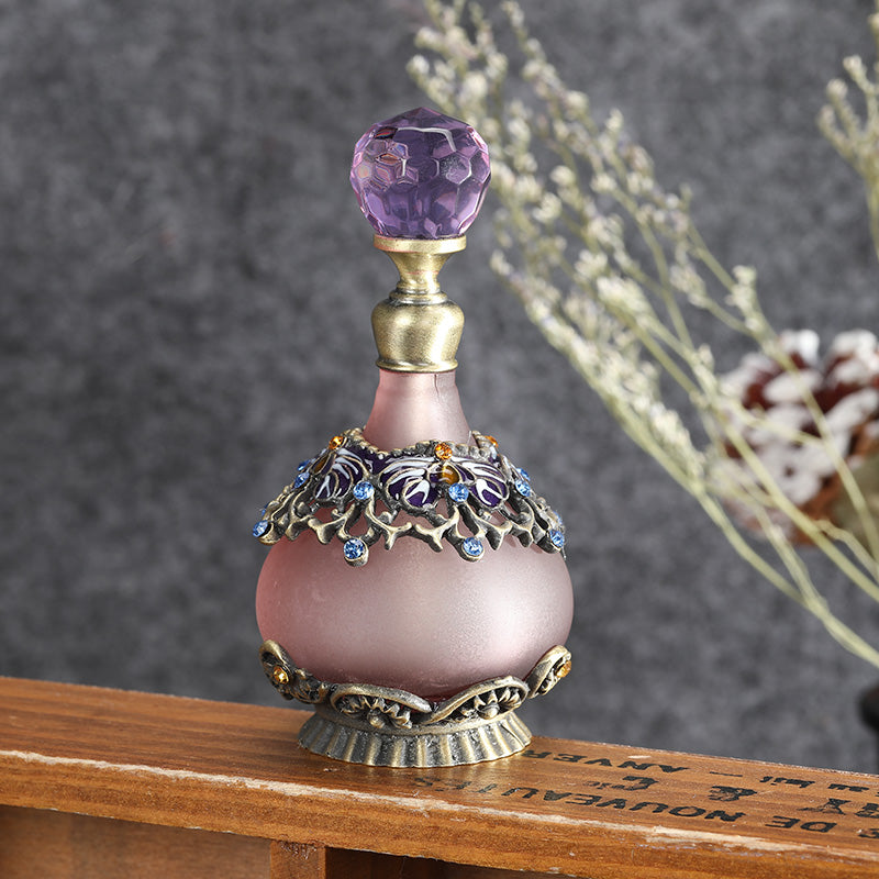 Purple-capped perfume oil bottle with mauve glass body and ornate blue floral metal collar