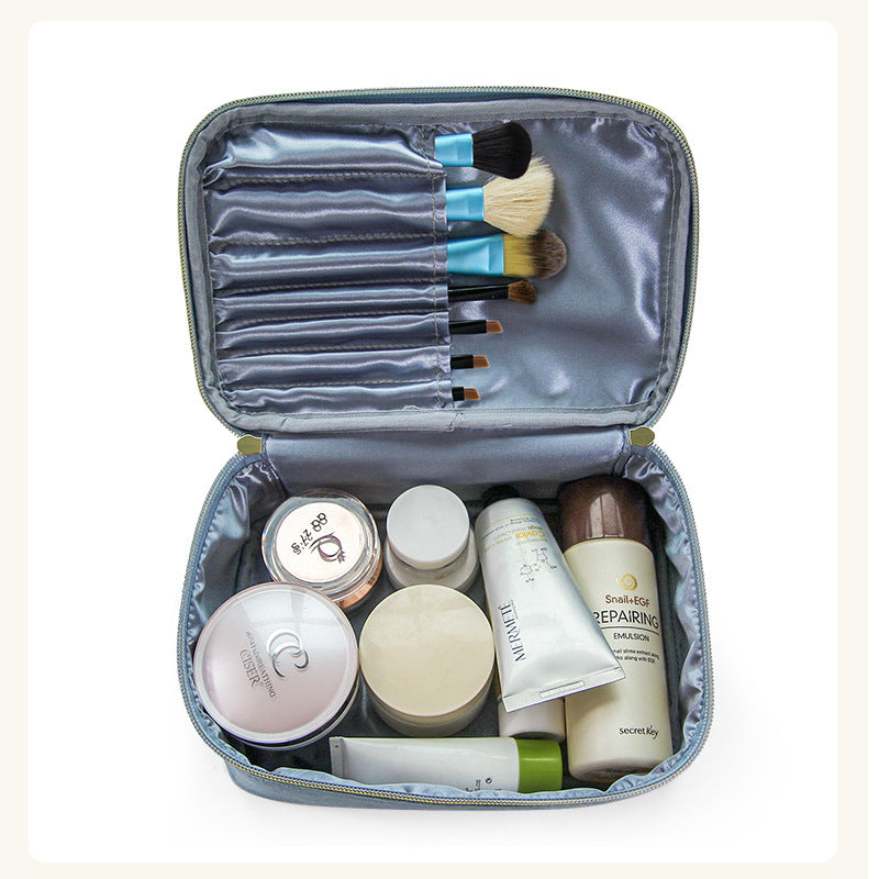 Soft travel cosmetic case open with makeup brushes and skincare bottles inside
