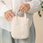 White travel vanity bag with top handles, stitched panels, and front logo patch.