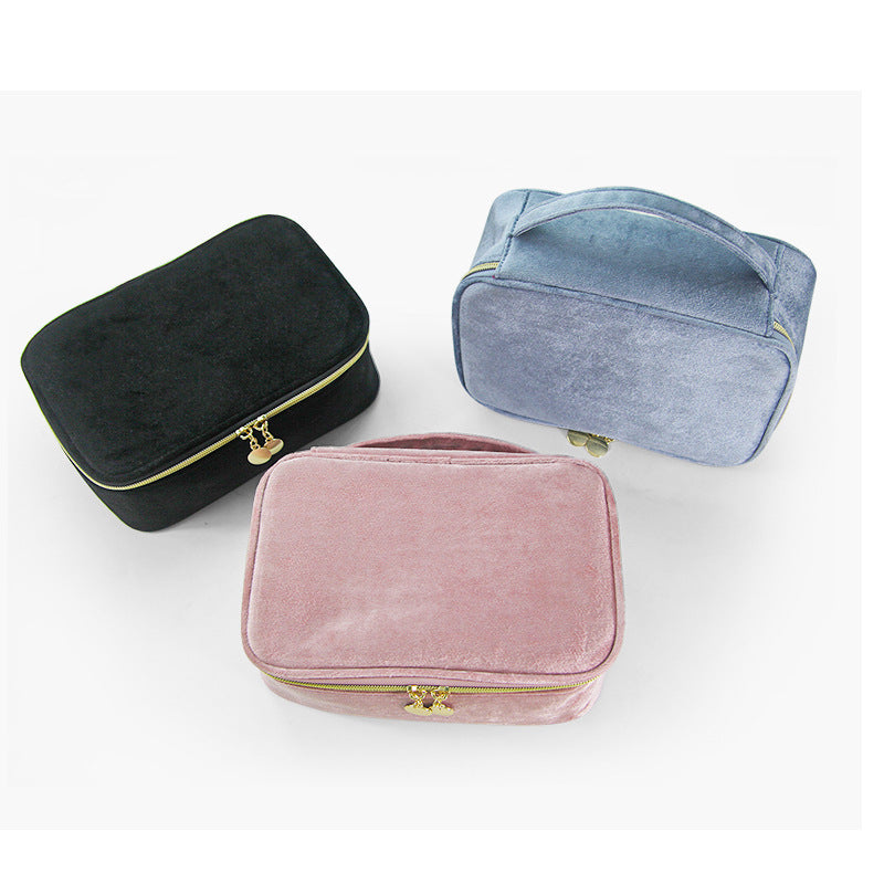 Soft travel cosmetic cases with zip top and gold hardware in black, blue, and pink