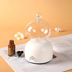 Aroma diffuser with white base, clear glass dome, and metal control knob