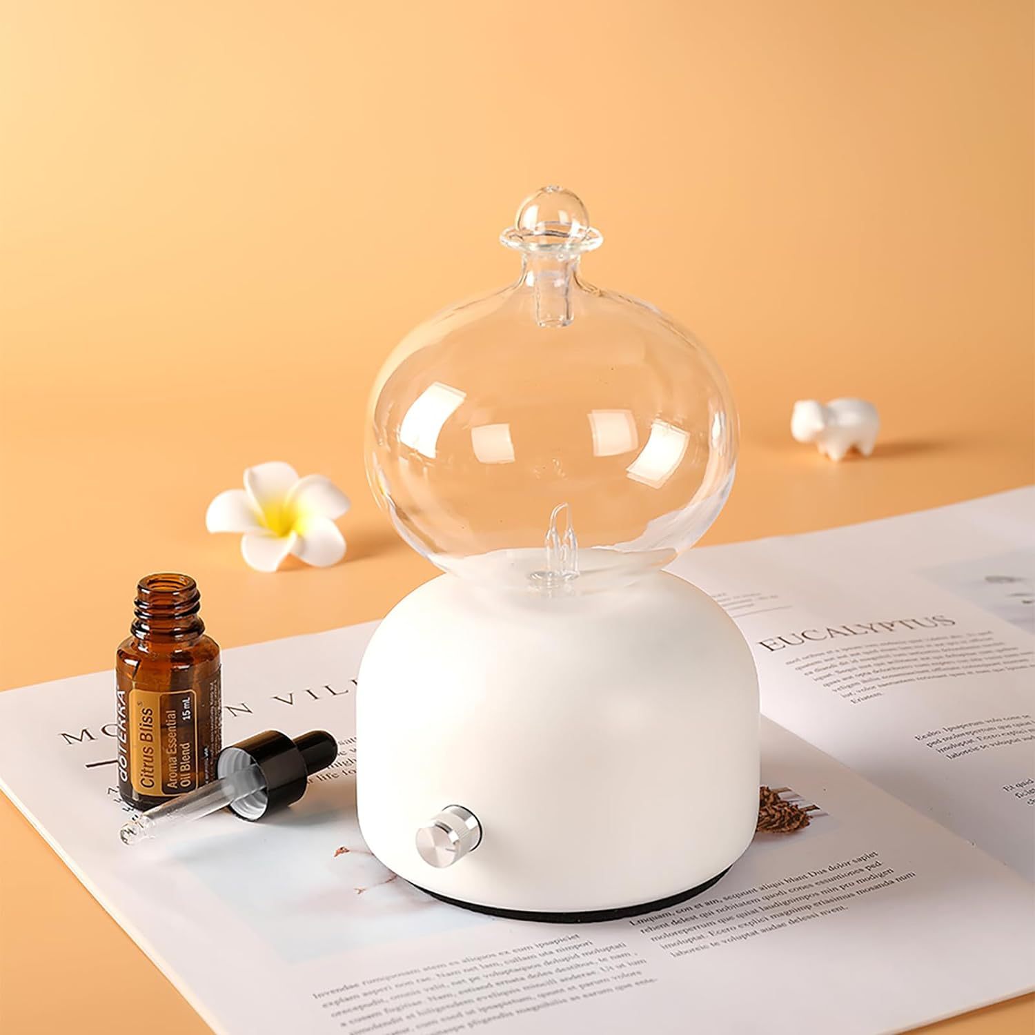 Aroma diffuser with white base, clear glass dome, and metal control knob