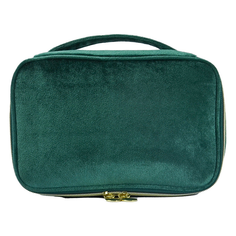 Soft travel cosmetic case in dark green with top handle and gold zipper pull