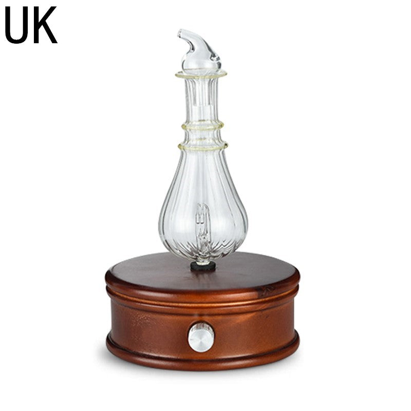 Aroma diffuser with clear glass spray bottle on dark wooden base, silver power button