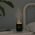 Black candle-style aroma diffuser jar releasing light mist