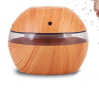 Wood essential oil diffuser with clear top band and front mist vent, seated on base