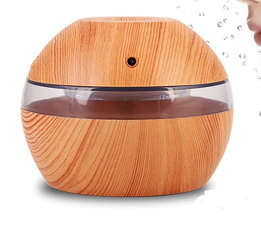 Wood essential oil diffuser with clear top band and front mist vent, seated on base