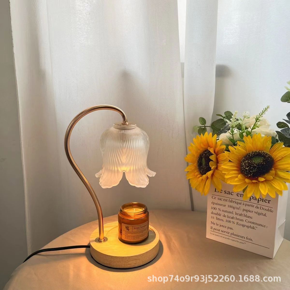 Aroma diffuser on wood-grain base with lit bell-shaped glass shade and amber candle jar