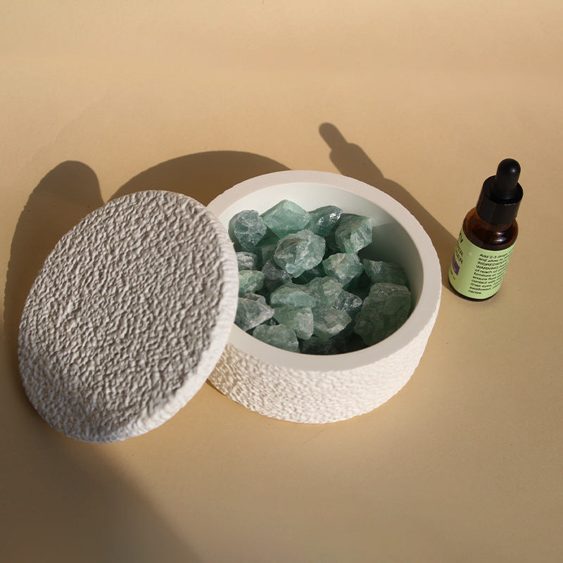 Stone crystal diffuser with green crystals in a white round base, gray textured lid