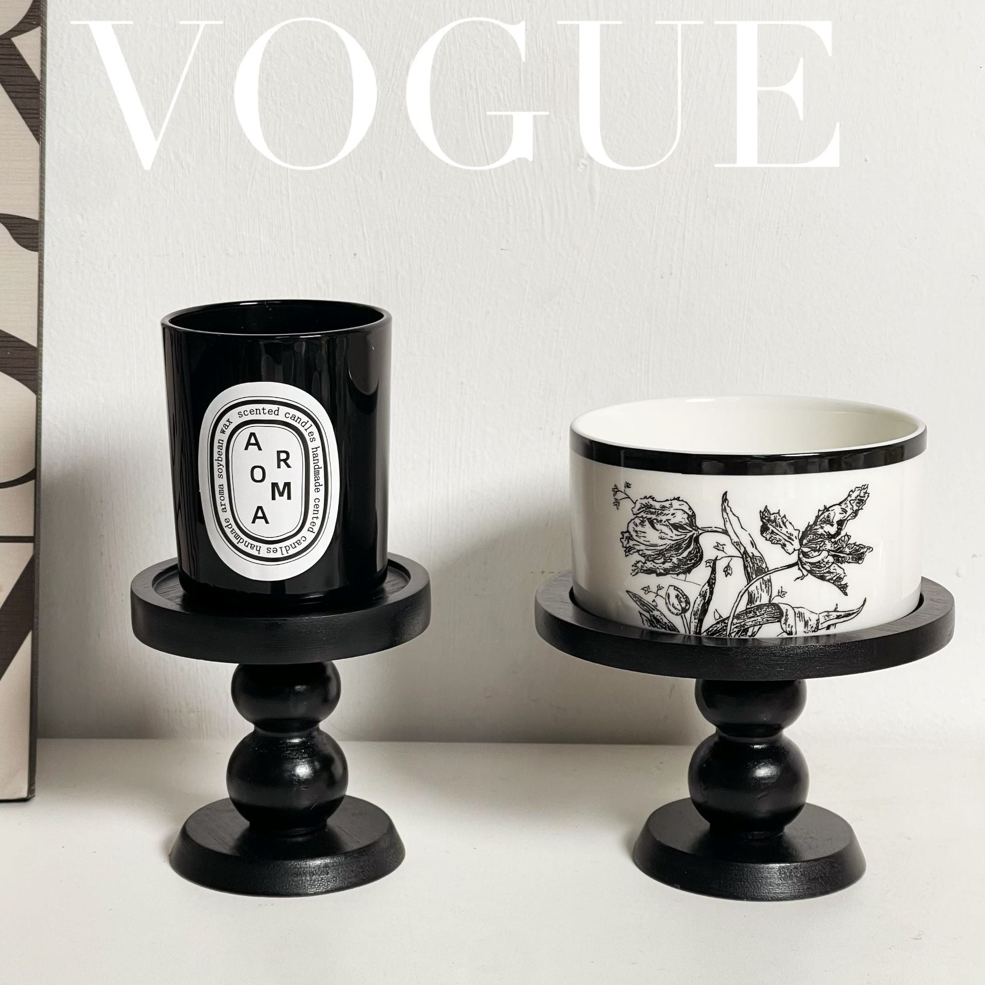 Black scent trays on pedestal bases holding two candle cups, one patterned