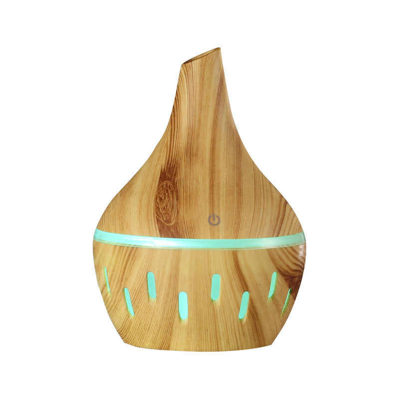 Wood grain aroma diffuser with teal LED light ring and power button, light wood finish.