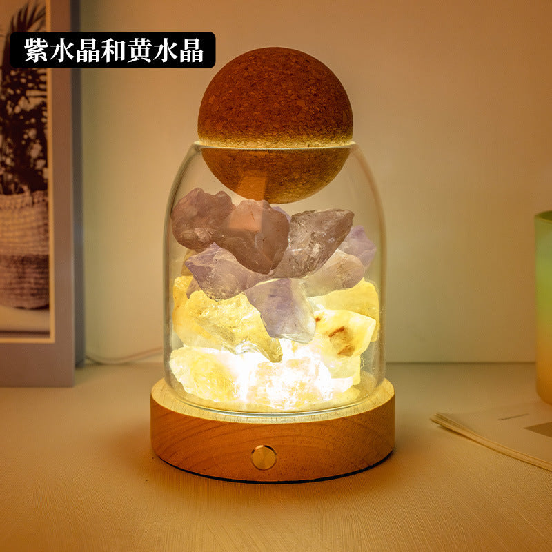 Crystal diffuser night light with yellow, purple, and clear crystal chunks on wooden base
