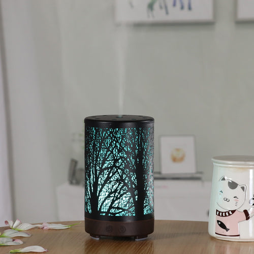 Mini aroma diffuser with dark base, glowing forest light pattern, top vents