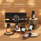 Essential oil bottles on wood slices beside a black gift box