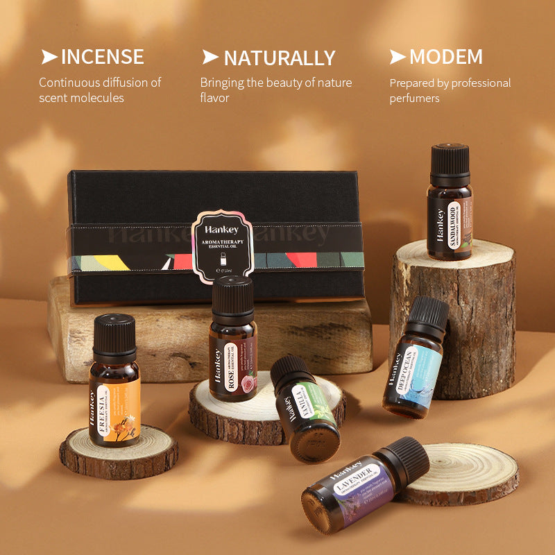 Essential oil bottles on wood slices beside a black gift box