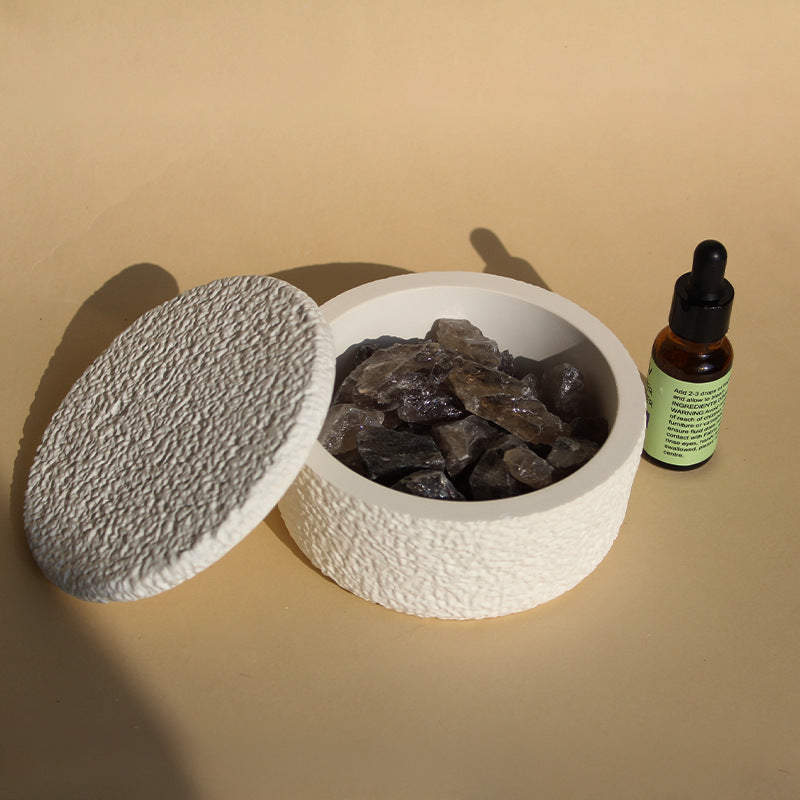 Stone crystal diffuser with dark gray crystals, white round base, and gray textured lid