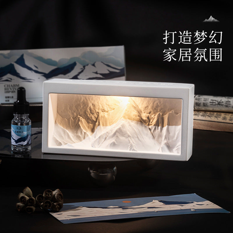 Rectangular crystal diffuser with glowing mountain-style insert and dark essential oil bottle