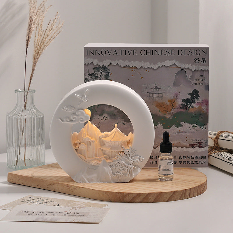 White round aromatherapy lamp with decorative landscape relief and essential oil bottle
