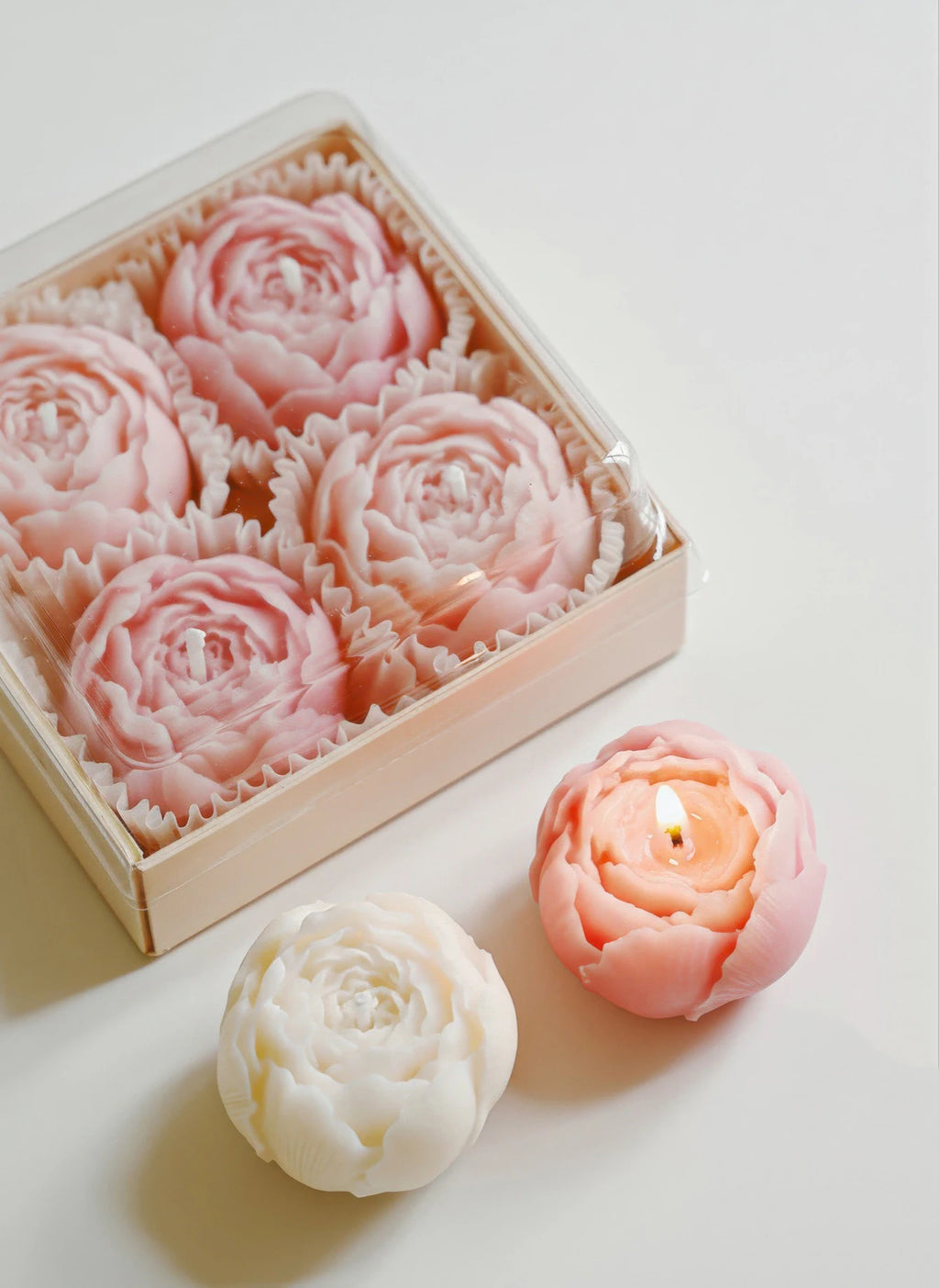 Open gift box with pink rose-shaped soy wax candles and one white candle