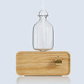 Essential oil diffuser with clear glass bottle on light wood base and round power dial
