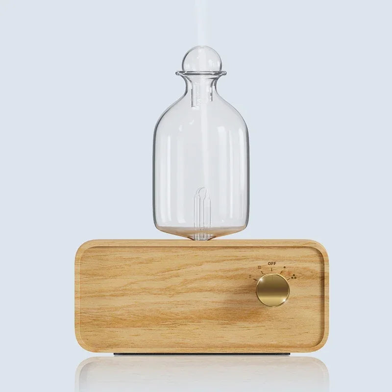 Essential oil diffuser with clear glass bottle on light wood base and round power dial