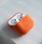 Alcantara AirPods case in amber orange, open front view with earbuds inside
